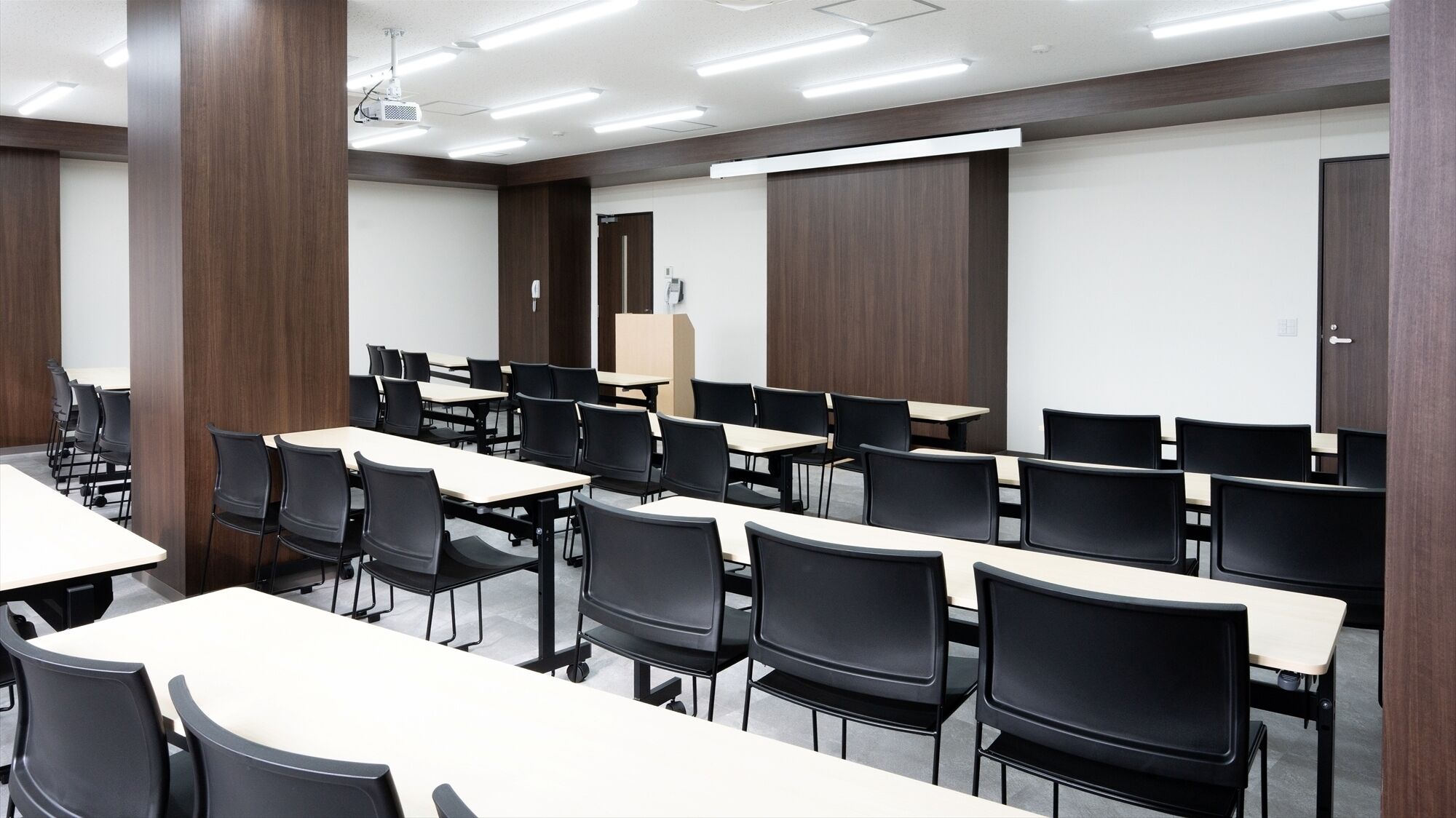Una sala conferenze con diversi tavoli e sedie, un proiettore e una lavagna.