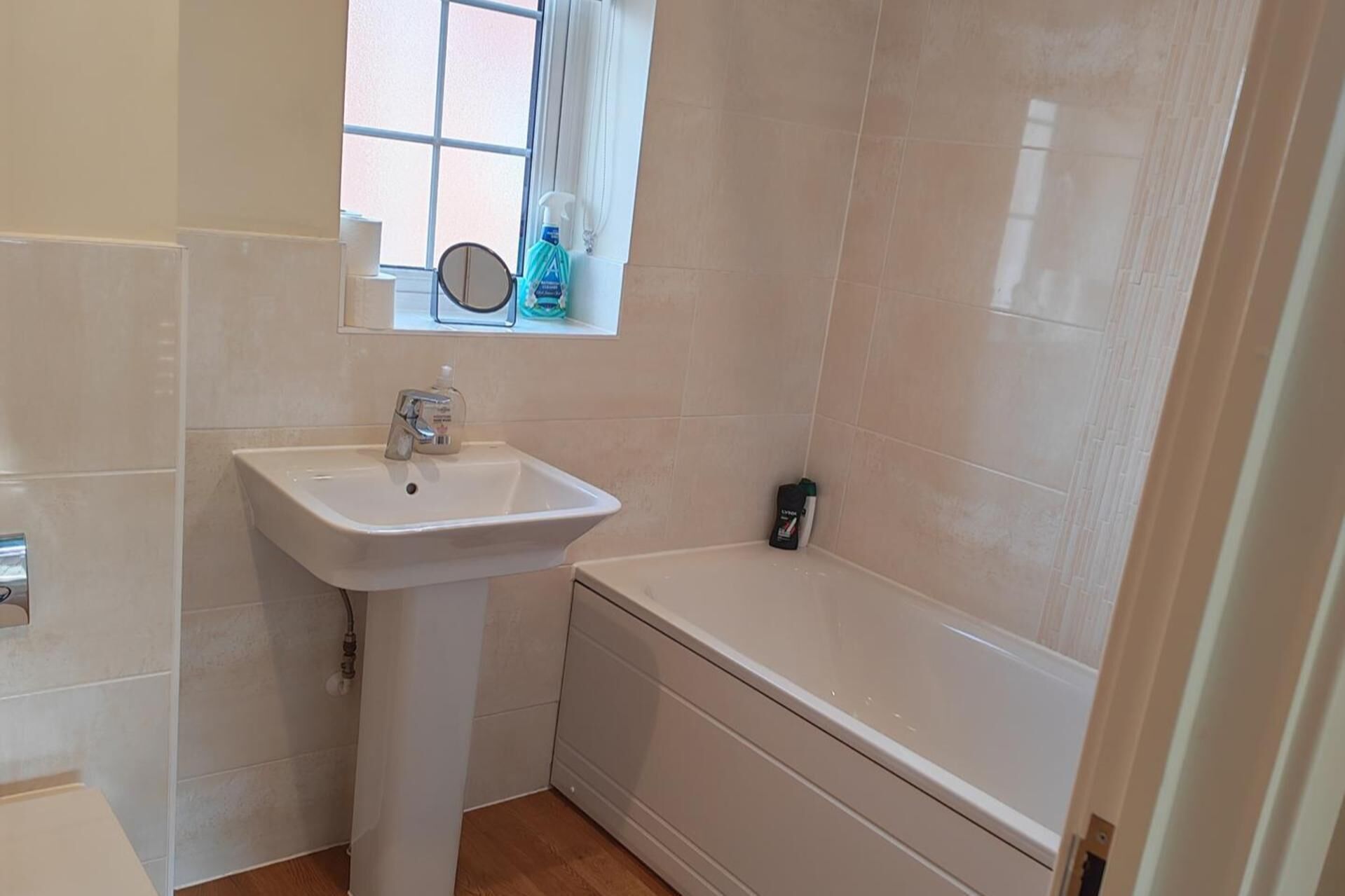 A bathroom with a sink, a window, and a bathtub.
