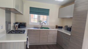 A modern kitchen with a gas stove, a built-in oven, a window with a view, and wooden cabinetry. - 3 Bedroom House Sleeps 7 - Pets Ok - Free Parking (Ashford)