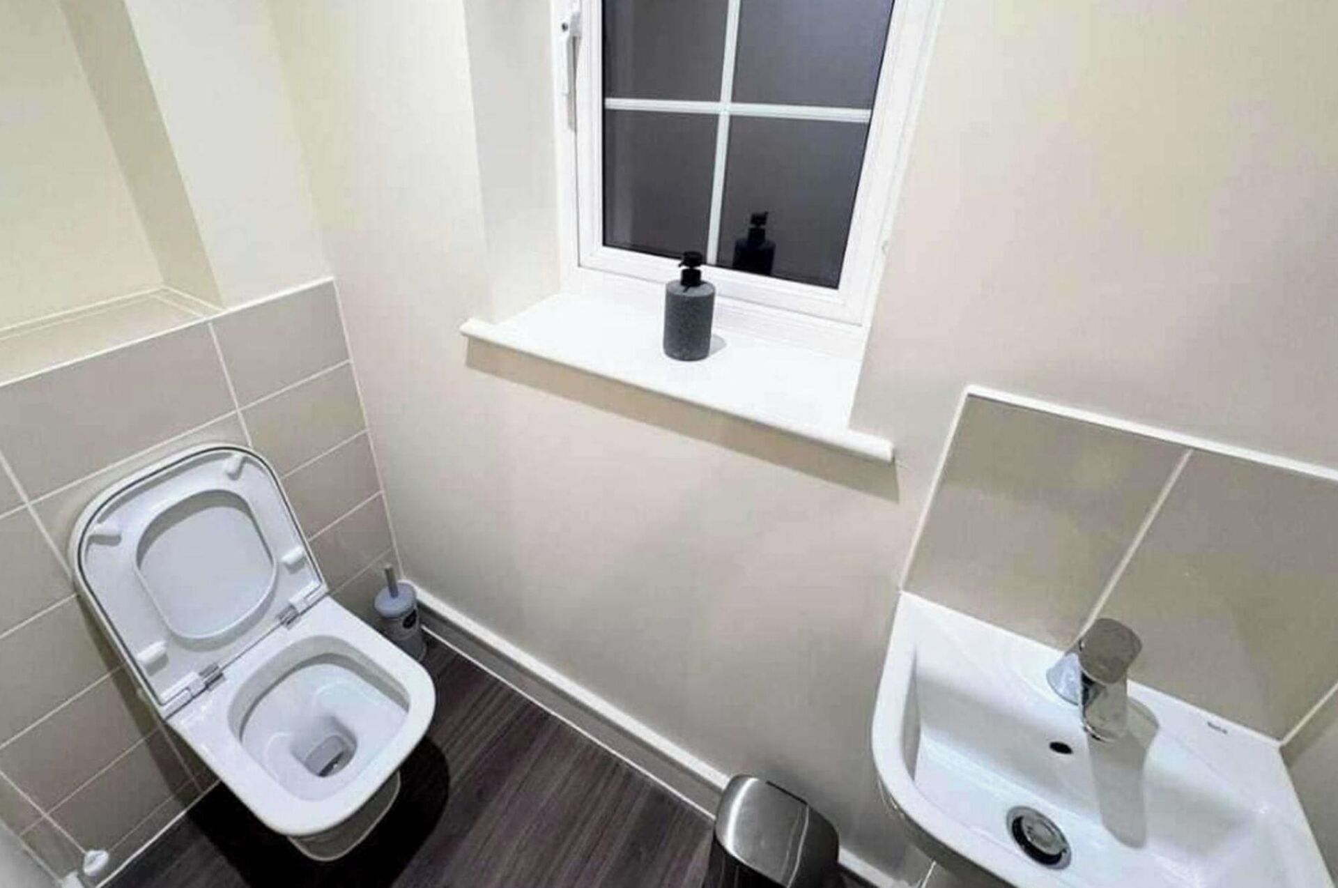 A small bathroom with a toilet, a window, and a sink.