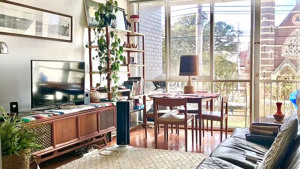 Ein Wohnzimmer mit Fernseher, Bücherregal und großem Fenster.