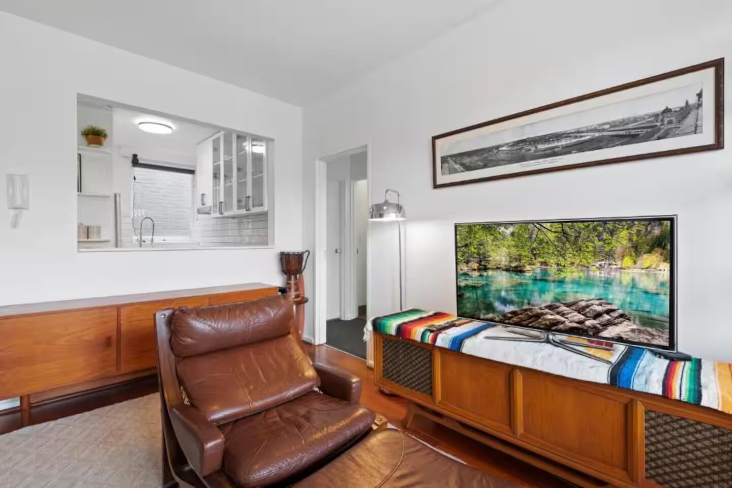 Un soggiorno moderno con un divano in pelle, una TV a schermo piatto e un'ampia finestra con vista su un'area esterna panoramica.