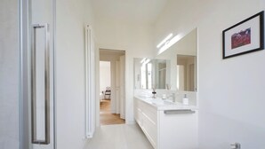 Une salle de bain moderne avec un meuble-lavabo blanc, un grand miroir et un bidet.