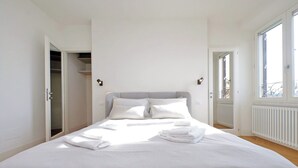 Une chambre avec un grand lit, une armoire et une fenêtre donnant sur un beau paysage.