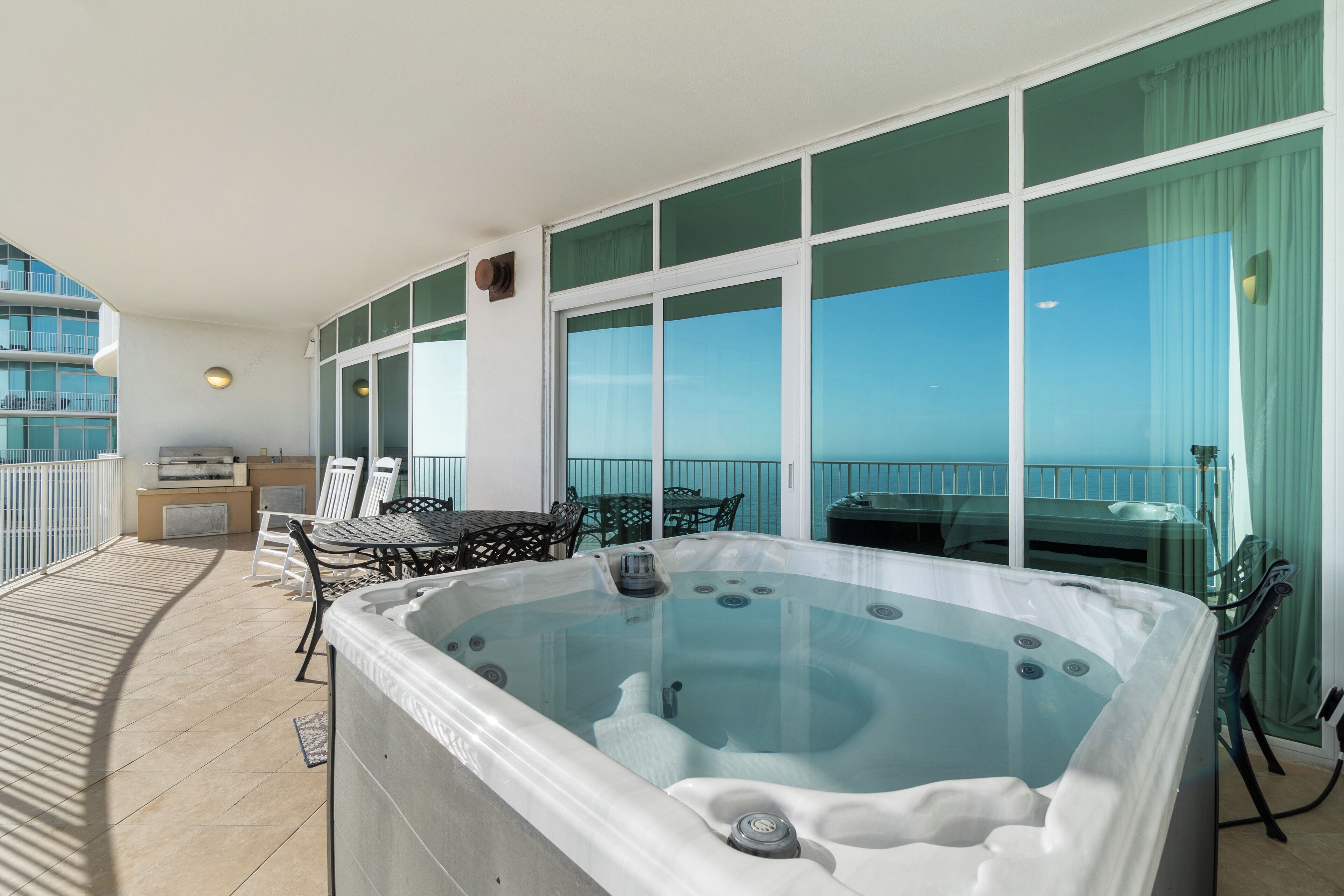 A balcony with a hot tub, outdoor seating, and a view of the sea.