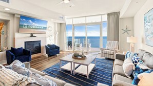 A spacious living room with a fireplace, a television, and a large window offering a view of the ocean. - Turquoise Place Beachside Retreat (Orange Beach)