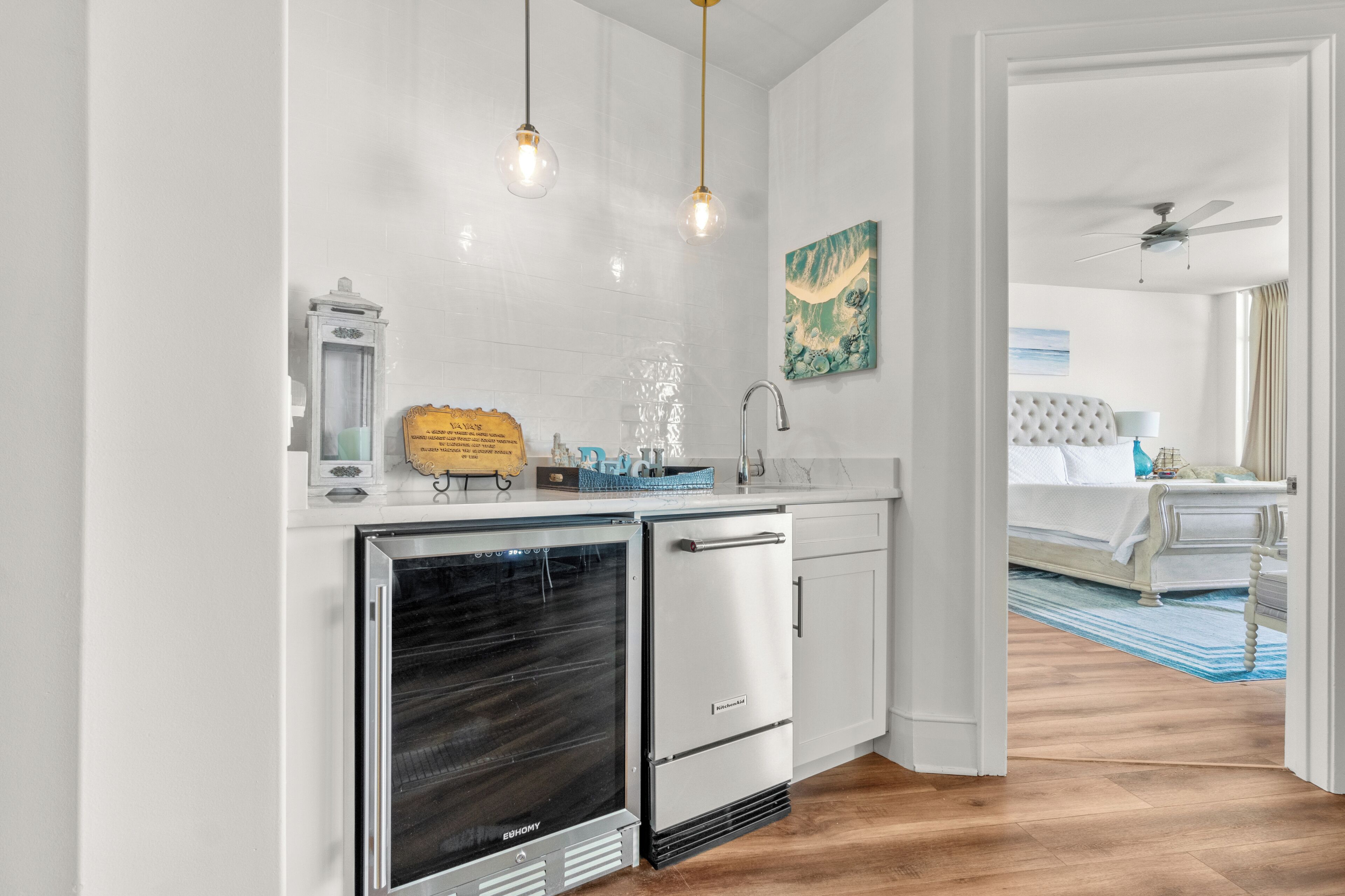 A modern kitchen with a built-in oven, a refrigerator, and pendant lights.