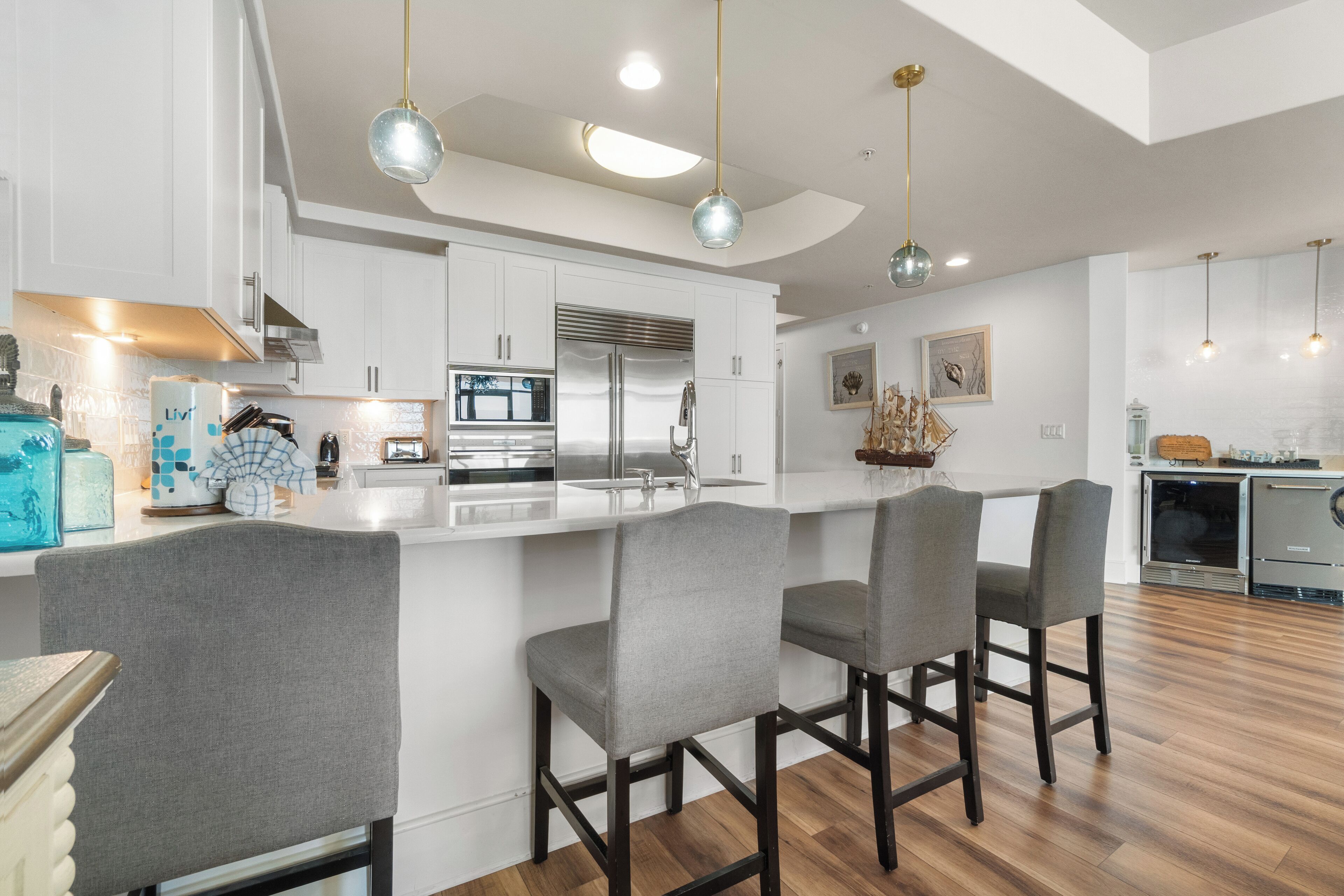 A modern kitchen with white cabinets, stainless steel appliances, and a central island with bar stools.