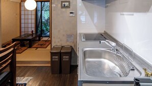 Een moderne keuken met een ingebouwde vaatwasser, een ruime gootsteen en een eethoek met een traditionele Japanse tafel en tatami matten.