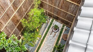 Een klein, omheind tuintje met verschillende planten en een ronde plantenbak.