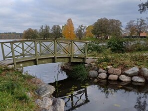 A wooden bridge over a pond with surrounding vegetation and trees. - 3 Person Holiday Home in Strangnas (Strängnäs)