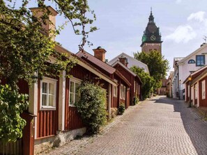 A cobblestone street lined with traditional red wooden houses, a prominent church tower in the background, and a clear blue sky. - 3 Person Holiday Home in Strangnas (Strängnäs)