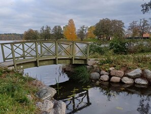 Un ponte di legno sopra uno stagno tranquillo, con rocce e vegetazione tutt'intorno.