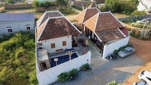 A residential property with a swimming pool, a covered patio, and a car parked in the driveway. - Teko Island (Siem Reap)
