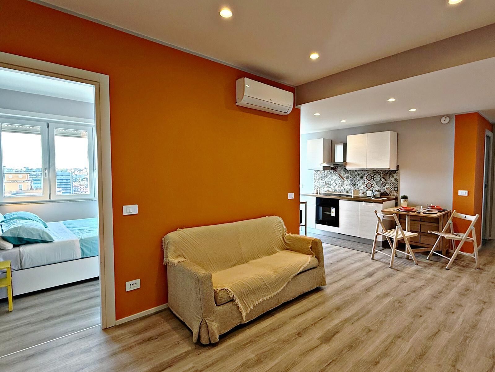 Um apartamento moderno com sala de estar, cozinha compacta e quarto com vista para a cidade.