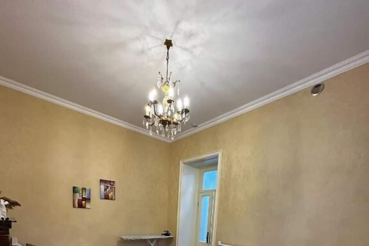 Une chambre d’hôtel avec deux lits simples, un bureau, une chaise, une petite table et un lustre.
