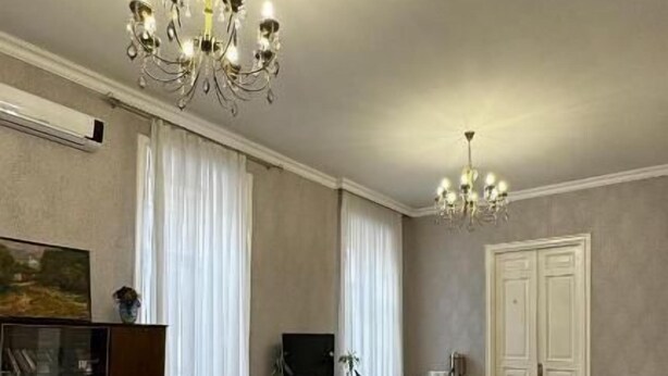 Ein geräumiges Wohnzimmer mit Essbereich, Holzboden und zwei Kronleuchtern.