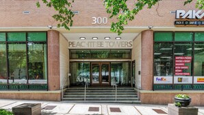 Het uiterlijk van Peachtree Towers, een gebouw met een bakstenen gevel, grote ramen en een bord dat aangeeft dat het een FedEx Erkend Verzendcentrum is.