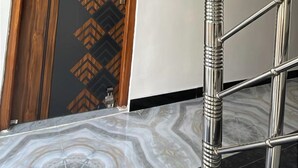 Ein modernes Hotelzimmer mit einem marmorierten Boden, einer Holztür mit geometrischem Muster und einer Metalltreppe mit runder Handlauf.