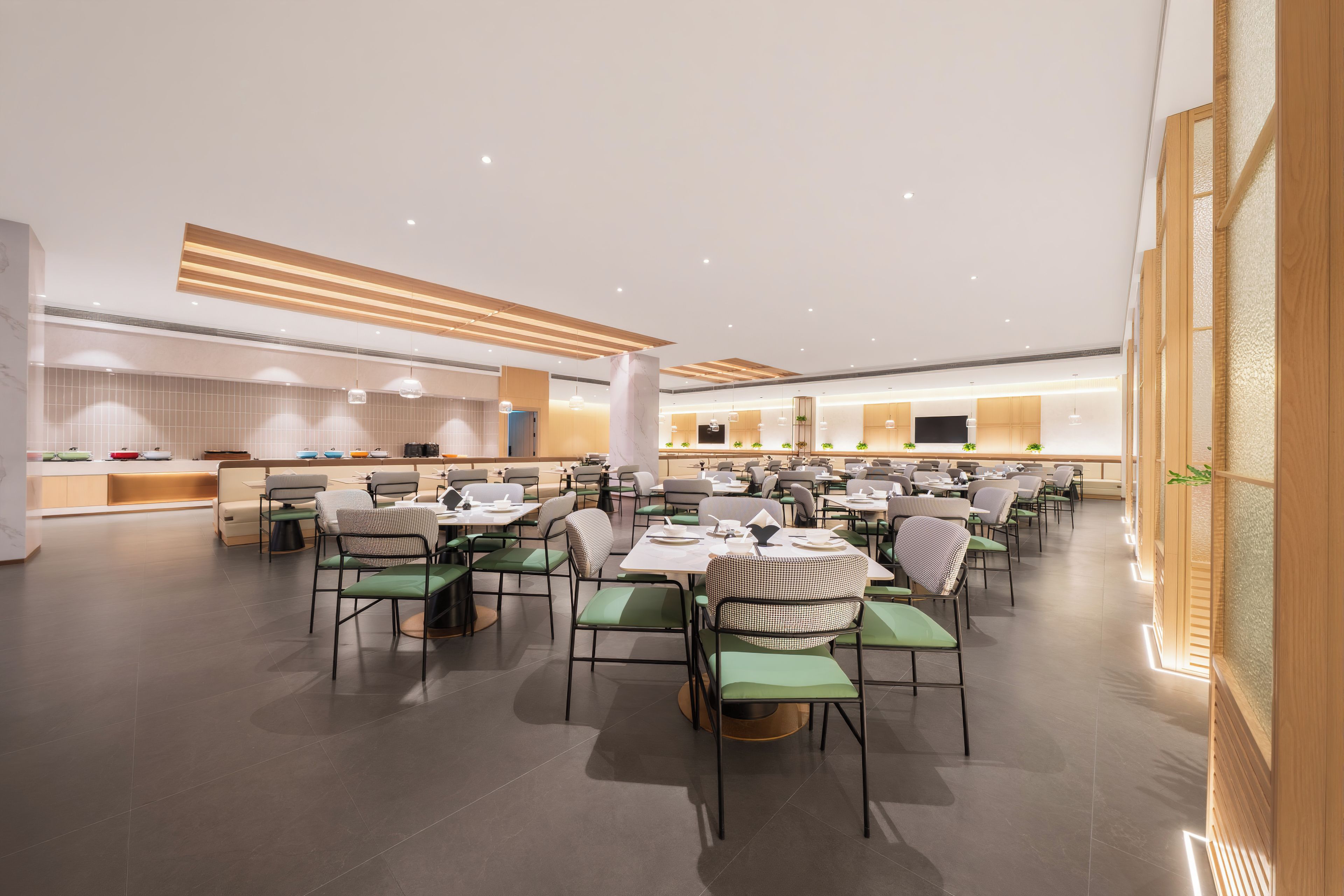 A spacious dining area with multiple tables and chairs, a kitchen in the background, and a modern ceiling design.