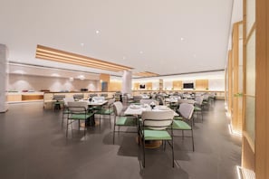A spacious dining area with multiple tables and chairs, a kitchen in the background, and a modern ceiling design. - Shanghai Joy International Resort Hotel (Wild Animal Park) (Shanghai)