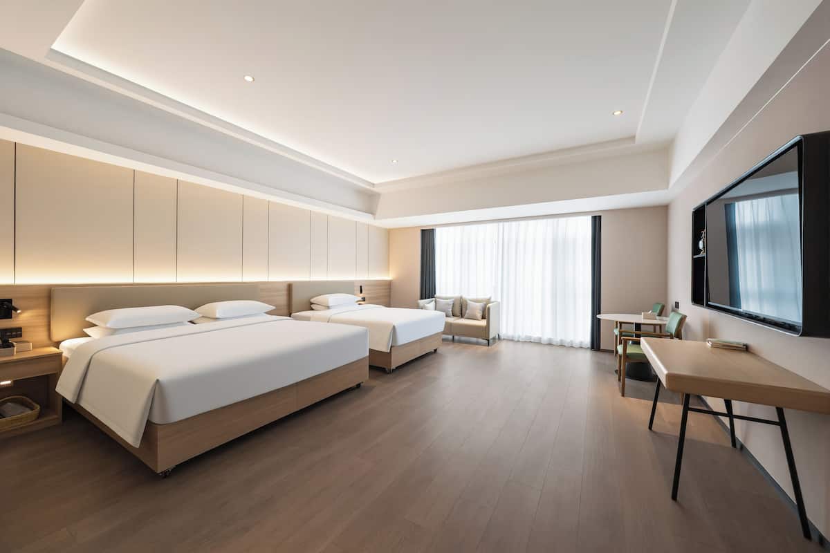 Quarto de hotel moderno com uma cama grande, uma escrivaninha e uma televisão.