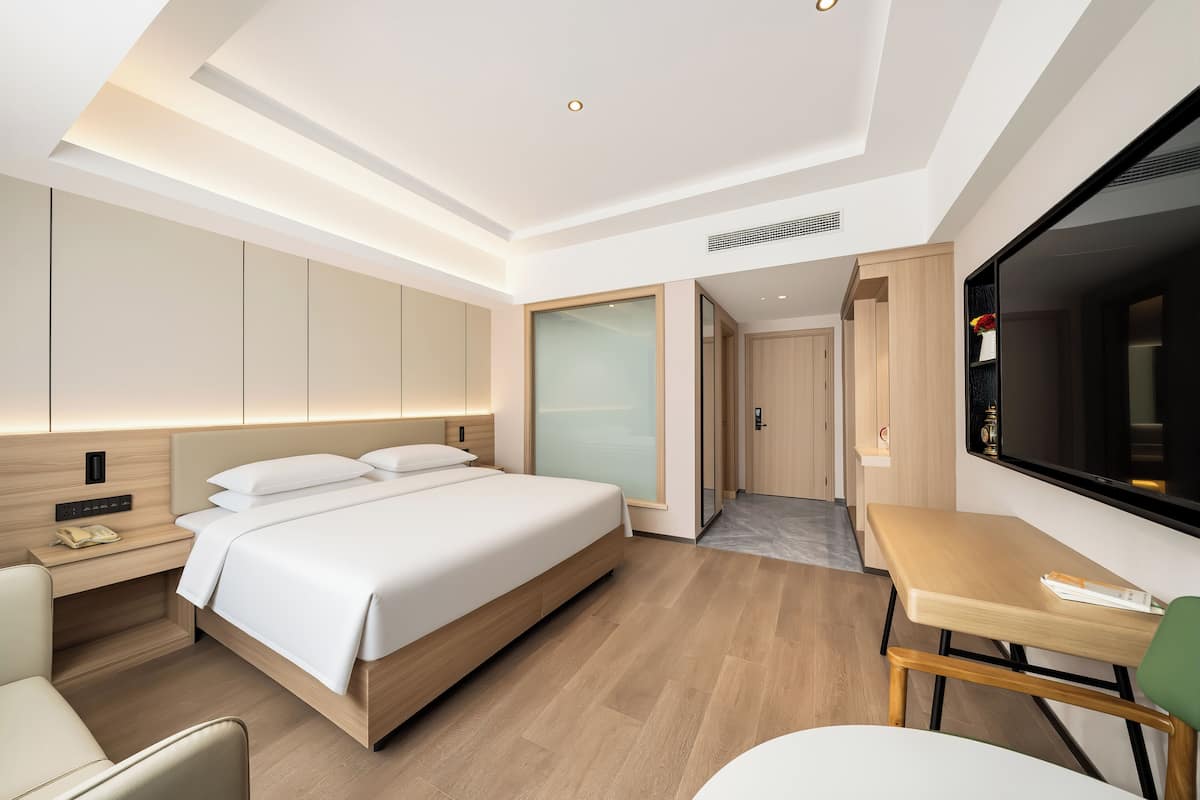 Quarto de hotel moderno com uma cama grande, uma escrivaninha e uma televisão.