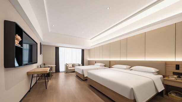Een moderne hotelkamer met een houten vloer, twee bedden, een bureau en een aan de muur bevestigde televisie.