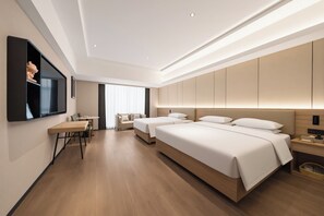 Una habitación de hotel moderna con suelo de madera, dos camas, un escritorio y un televisor montado en la pared.