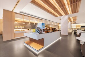 A modern hotel lobby with a central reception desk, seating area, and a kitchen in the background. - Shanghai Joy International Resort Hotel (Wild Animal Park) (Shanghai)