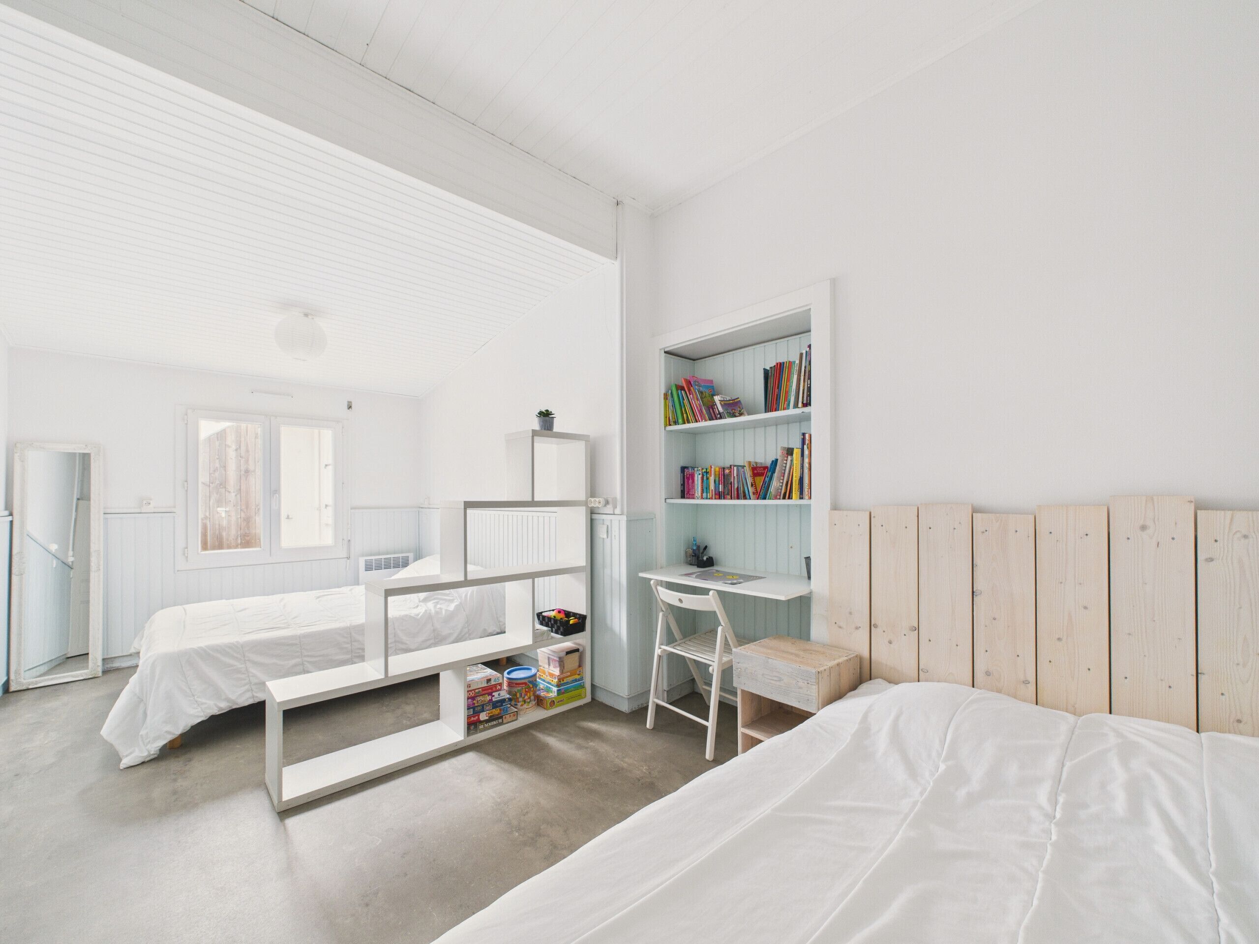 A minimalist bedroom with a bunk bed, a desk, and a bookshelf.