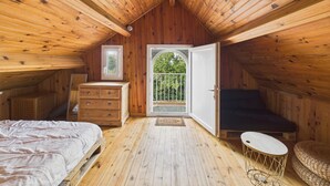 Een gezellig zolderkamer met houten wanden en een schuine plafond, met een bed, een kapstok en een klein rond tafeltje.