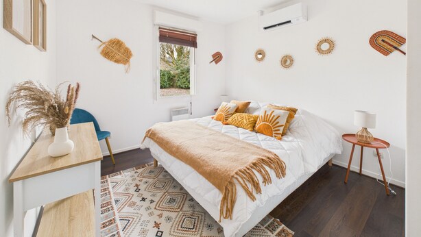 Un dormitorio con cama, escritorio, silla, ventana y decoración mural.