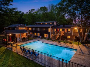 Una casa grande con piscina, varias terrazas y mobiliario exterior.