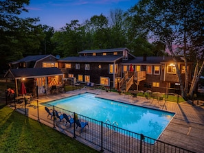 A large house with a swimming pool, multiple decks, and outdoor furniture.