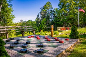 Un terrain de jeu de shuffleboard à carreaux, doté de barrières en bois et d’un mât portant le drapeau américain.