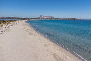 A beach with clear water, a stone wall, and distant mountains. - Villa 'Luna with Shared Pool', Mountain View, Wi-Fi and Air Conditioning (Buddittogliu Straulas)