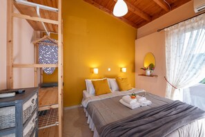 Un dormitorio con techo de madera, cama con almohadas blancas y mostaza, mesita de noche con control remoto y ventana con cortinas.