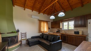 Een gezellige woonkamer met een hoekbank, een open haard en een eethoek met een houten tafel en stoelen.