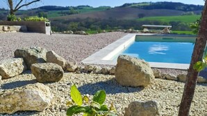 A swimming pool with a view of hills, surrounded by rocks and a tree. - Que Pour 2, Cottage/studio Le Bonheur, 1-bedroom with swimming pool and AC  Gers (Mauroux)