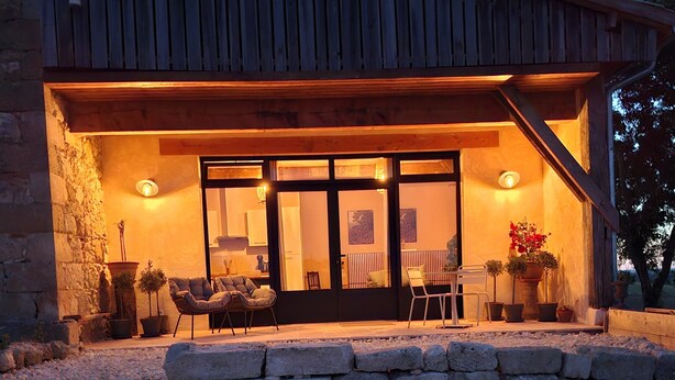 A rustic building with a stone facade, a wooden deck, and a glass door entrance. - Que Pour 2, Cottage/studio Le Bonheur, 1-bedroom with swimming pool and AC  Gers (Mauroux)