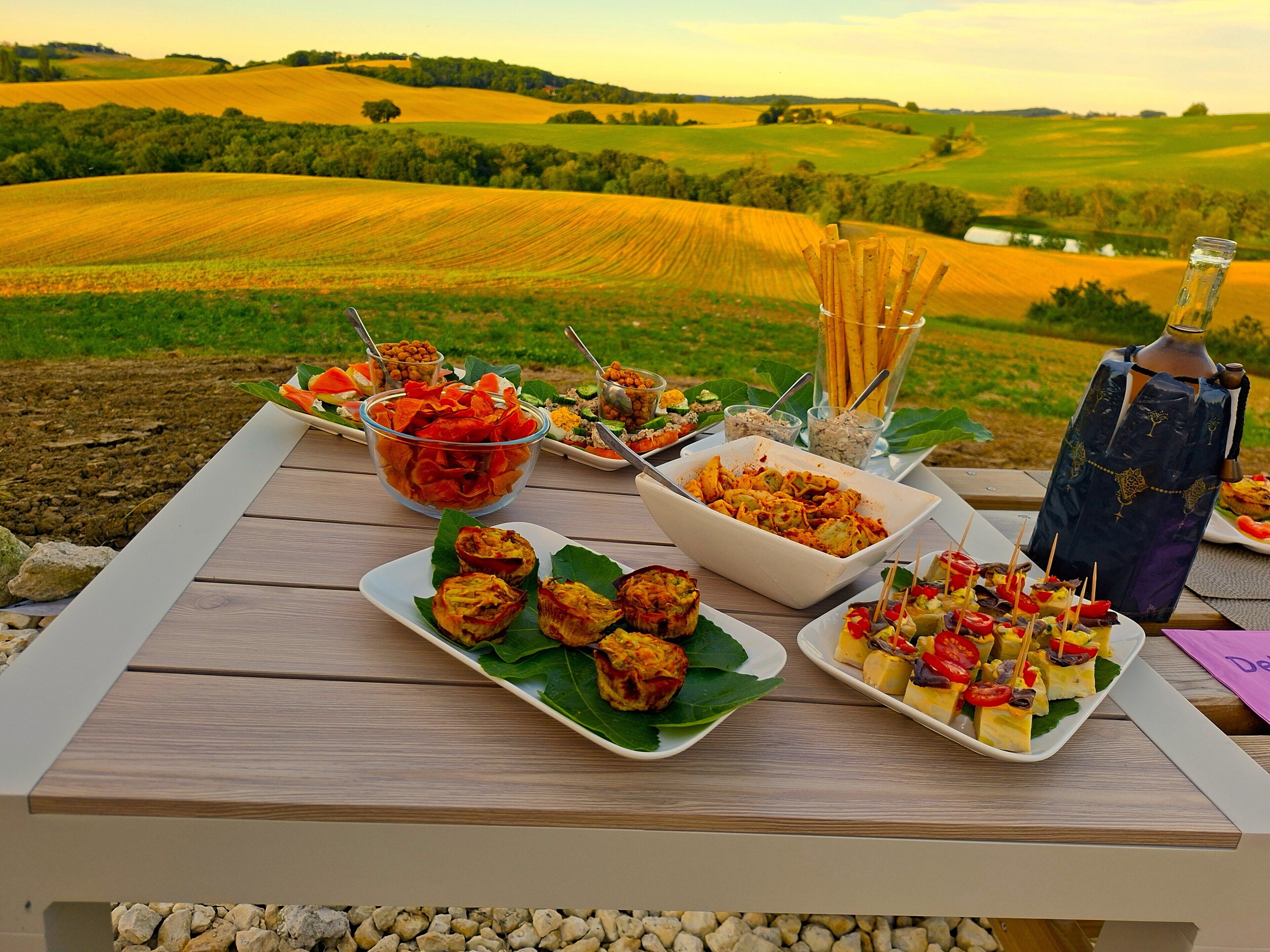 Une table dressée avec différents plats et une bouteille d’eau, offrant une vue sur un paysage magnifique.