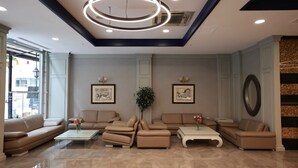 A modern lobby with beige sofas, a central plant, and framed artwork on the walls. - GOLDEN PARK HOTEL (İstanbul)