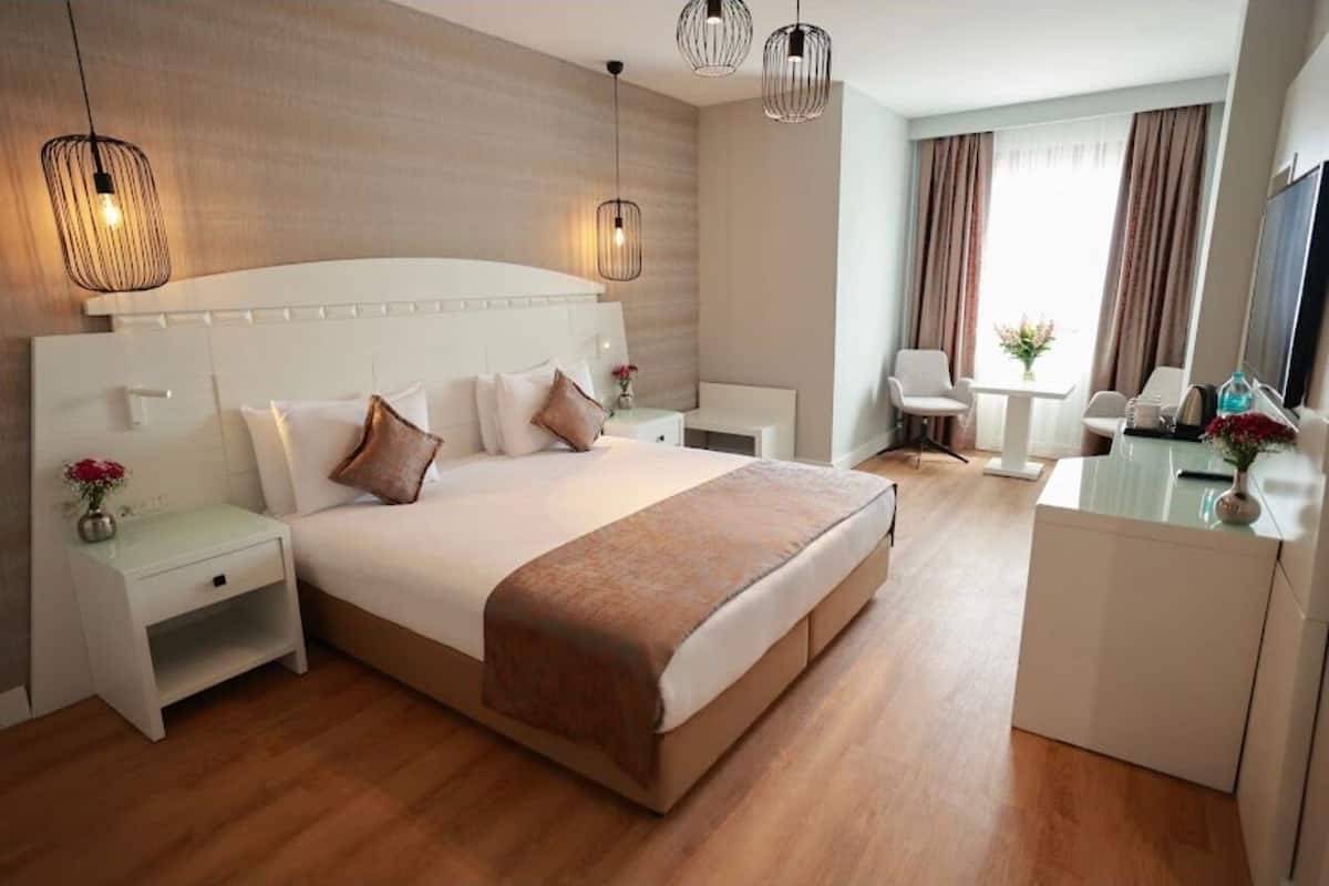 A hotel room with a large bed, bedside tables, a desk, and a chair.