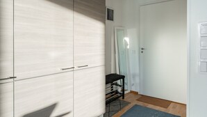 Een gang met een kast, een deur, een bankje en een vloermat.