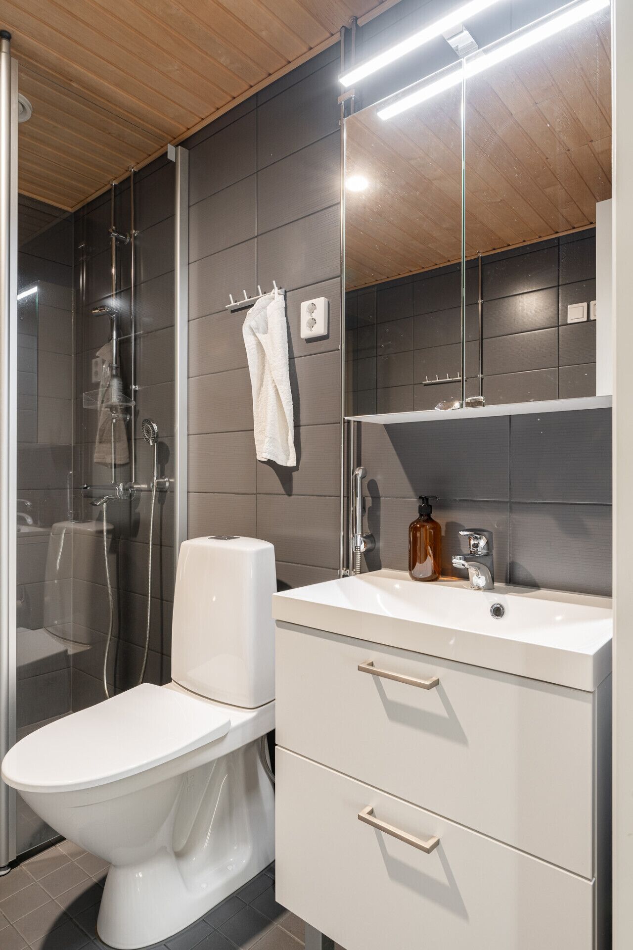 Une salle de bain moderne équipée de toilettes, d’une douche et d’un meuble-lavabo avec un miroir.