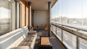 Een balkon met een bank, stoelen en een klein tafeltje.