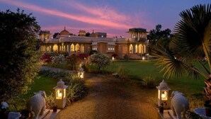 A grand building with a central dome and multiple smaller structures, surrounded by a well-maintained garden with pathways and decorative lanterns. - Dev Shree Deogarh (Devgarh)