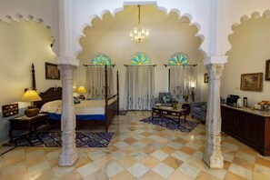 A traditional room with a bed, a desk, and a chandelier.