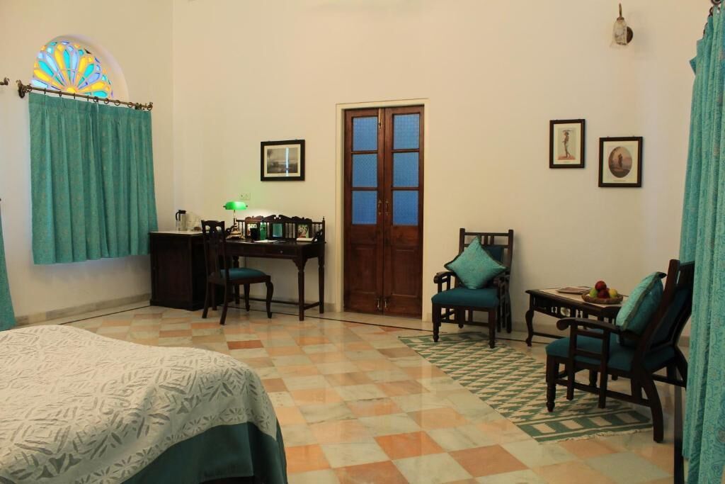 Una habitación con cama, escritorio, silla y puerta.